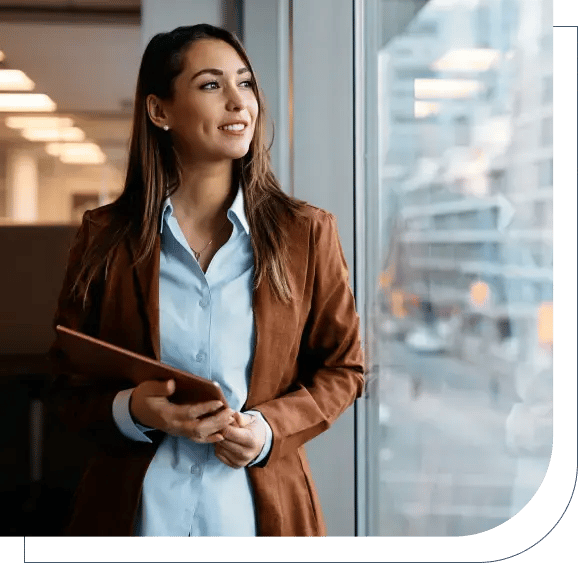 A female it manager looking outside a window while holding table